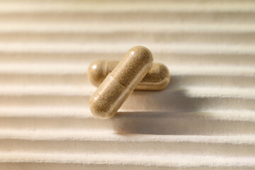 Close-up of two beige capsules on a textured surface symbolizes