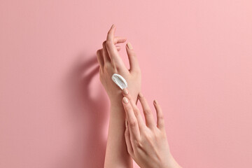 Hands Applying Moisturizing Cream on Soft Pink Background