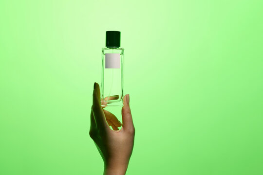 Sophisticated hands gracefully holding a perfume bottle, set aga