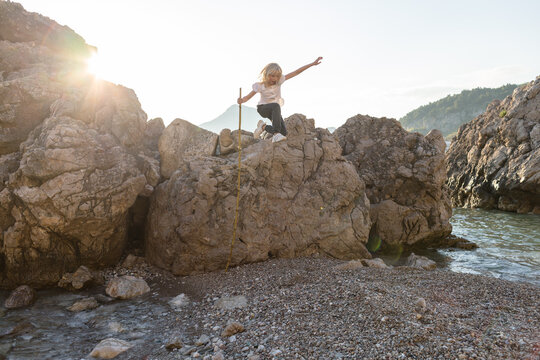 Little girl jumpung from a rock by the sea