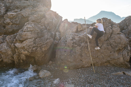 child climbs a rock by the sea