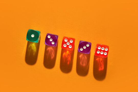 Colorful dice casting vibrant shadows on an orange background