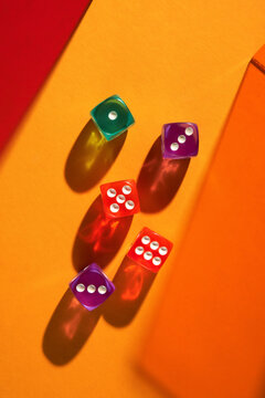 Colorful dice casting vibrant shadows on an orange background