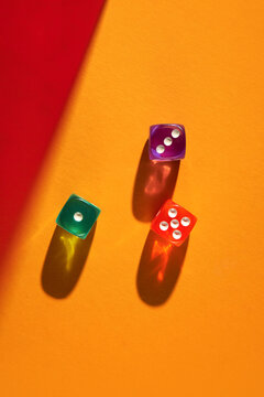Colorful dice casting vibrant shadows on an orange background