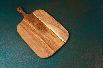 Wooden cutting board placed on a smooth green countertop