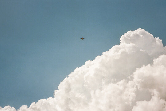 A passenger plane in the sky next to a big cloud. 