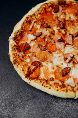 Delicious pizza with pepperoni and sausage on a black background