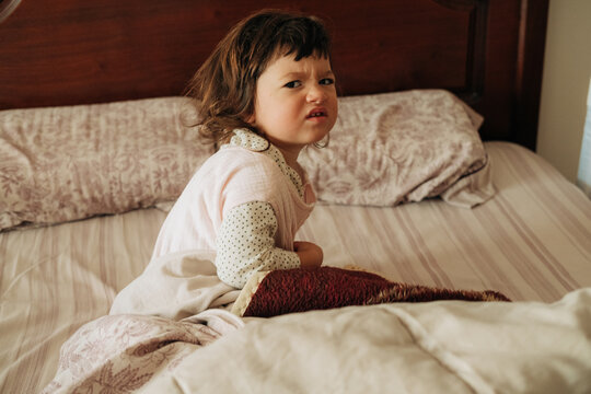 Grumpy toddler waking up in bed in the morning