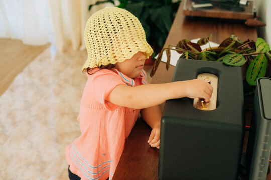 Curious toddler adjusting speaker knob indoors