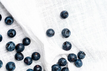 Blueberries scattered on a white cloth in a bright kitchen setting