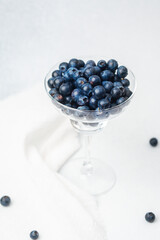 Fresh blueberries in a clear glass dish on a white surface