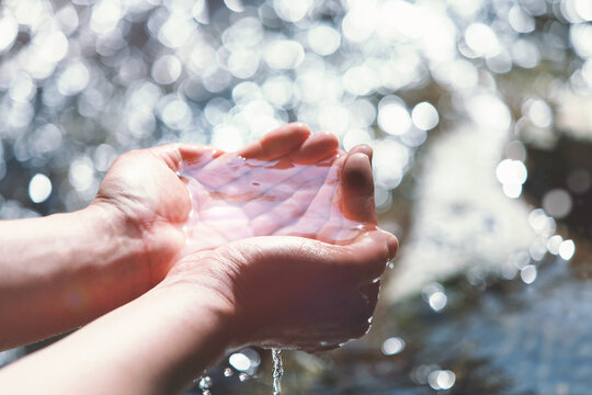 Clear and clean spring water in your hand, the water of life background

