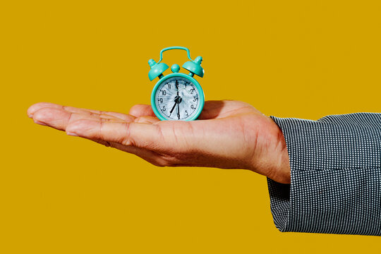 man with an alarm clock with broken glass on his palm