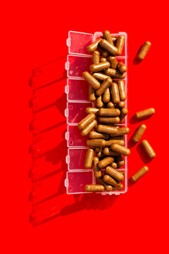 Daily pill organizer full with brown capsule pills
