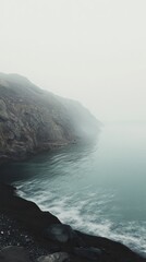 Misty Coastal Scenery: Dramatic Fog Over Dark Volcanic Beach