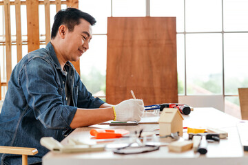 Smiling father focused on crafting a wood project at home workshop, surrounded by hand tools and models, celebrating Father’s Day through creative carpentry and DIY hobby inspiration.