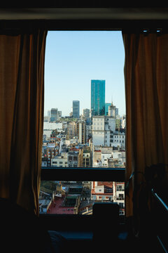 Skyline unveiling through apartment window with curtains