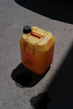 Yellow container left in a shadow on a concrete surface 