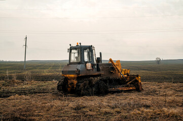 Fototapeta premium A bulldozer in a field in mud in cloudy weather