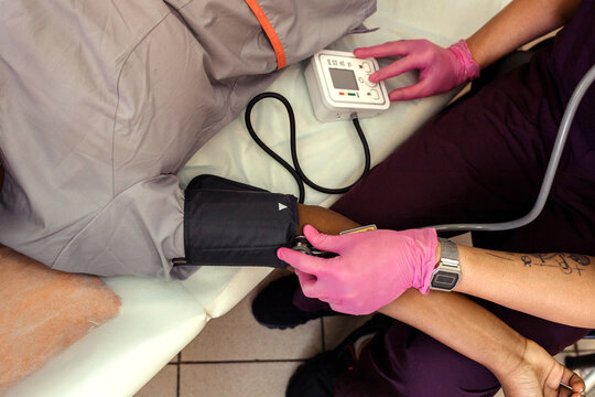Doctor measuring blood pressure of African woman at hospital.
