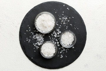 A wooden bowl of salt crystals on a wooden background. Salt in rustic bowls, top view with copy...