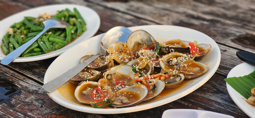 Fresh Spicy clam stir fried in oyster sauce with chilli on the timber table