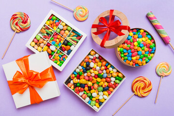 Set of different sweet candy in a paper box with a satin ribbon on a colored background. Holiday concept