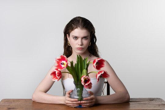 Portrait of young woman with red tulips flowers