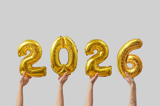 Women holding balloons in shape of 2026