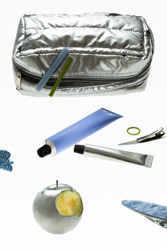 A silver cosmetic bag with neatly arranged tubes of cream and hairpins