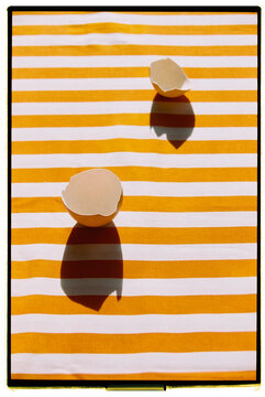 Still life with empty eggshells rest on a striped orange fabric