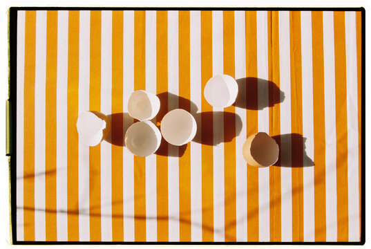 Empty eggshells rest on a striped orange fabric