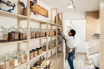 Employee Organizing Jars on Shelves in Bulk Food Store