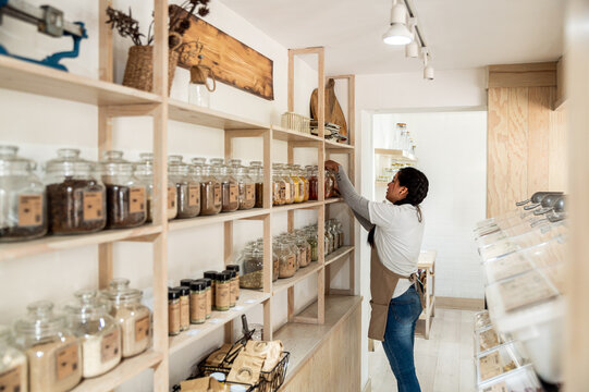 Employee Organizing Jars on Shelves in Bulk Food Store