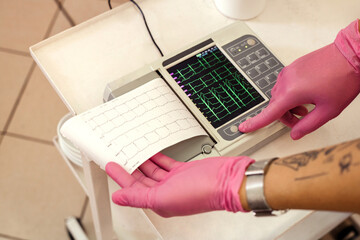 A cardiologist makes cardiogram by cardiograph at hospital.