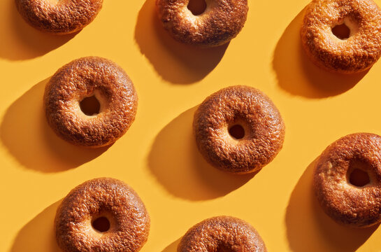 Freshly baked bagels making pattern on a bright yellow background.