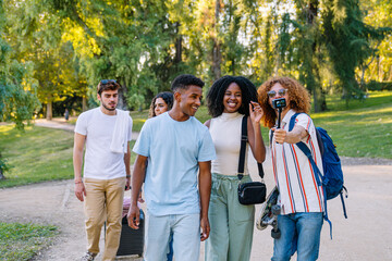 Happy multi ethnic friends filming a video blog while walking in a park during their summer vacation