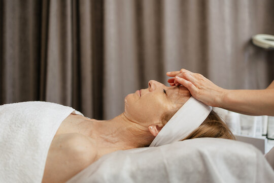 Unrecognizable beautician massaging mature woman