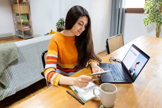 Woman booking holidays at home on laptop