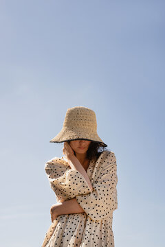 Woman in straw hat against blue sky.