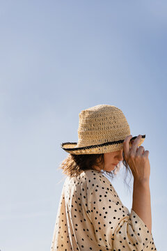 Woman in straw hat against blue sky.