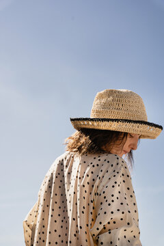 Woman in straw hat against blue sky.