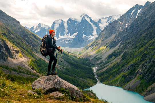 A tourist girl with a backpack stands on an observation deck overlooking Lake Shavlinsky in Altai
