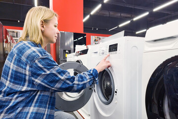 Woman with washing machine in electronics store