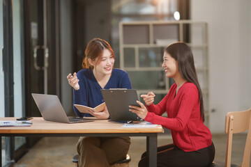 Group of Asian businesswomen working on documents in an office.