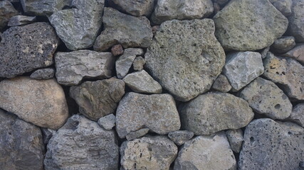 A high-quality stock image showcasing an old dry stone wall with irregular rocks, highlighting its rough texture and organic arrangement. Ideal for historical themes.