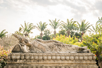 Reclining Buddha sculpture in Buddha Park with tropical garden