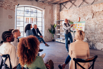 Senior manager using kanban board presenting business strategy to diverse team in loft office