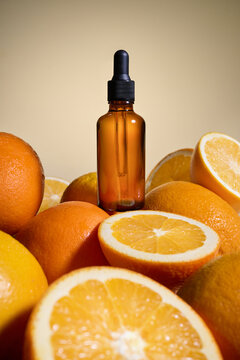 An amber bottle with a dropper surrounded by fresh oranges