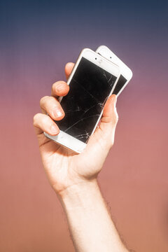 Hand holding broken smartphones